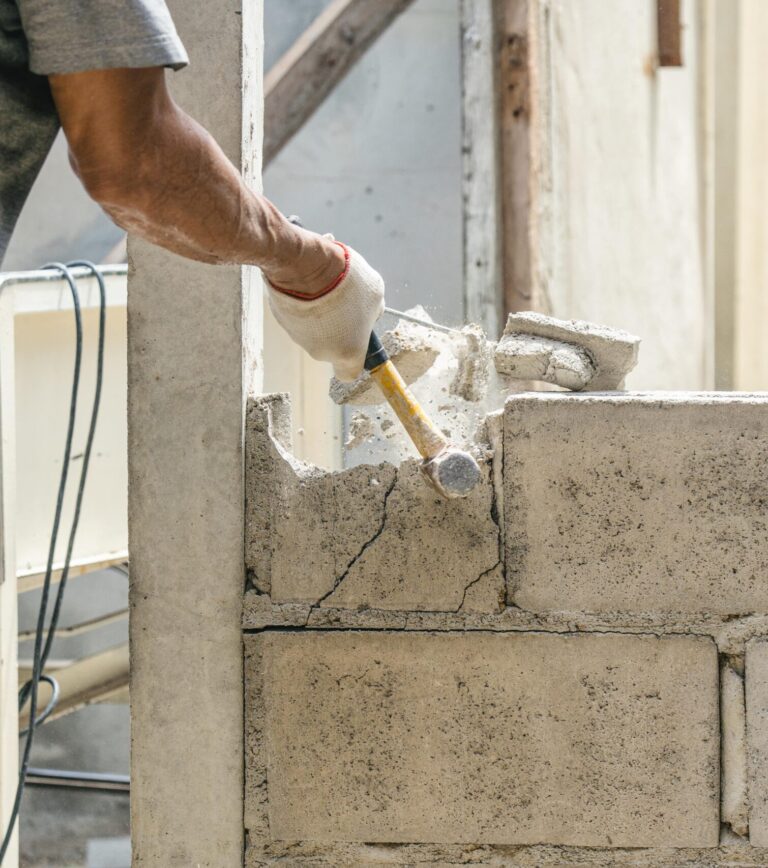 hand-worker-using-hammer-smashing-demolish-brick-wall-construction-site-min