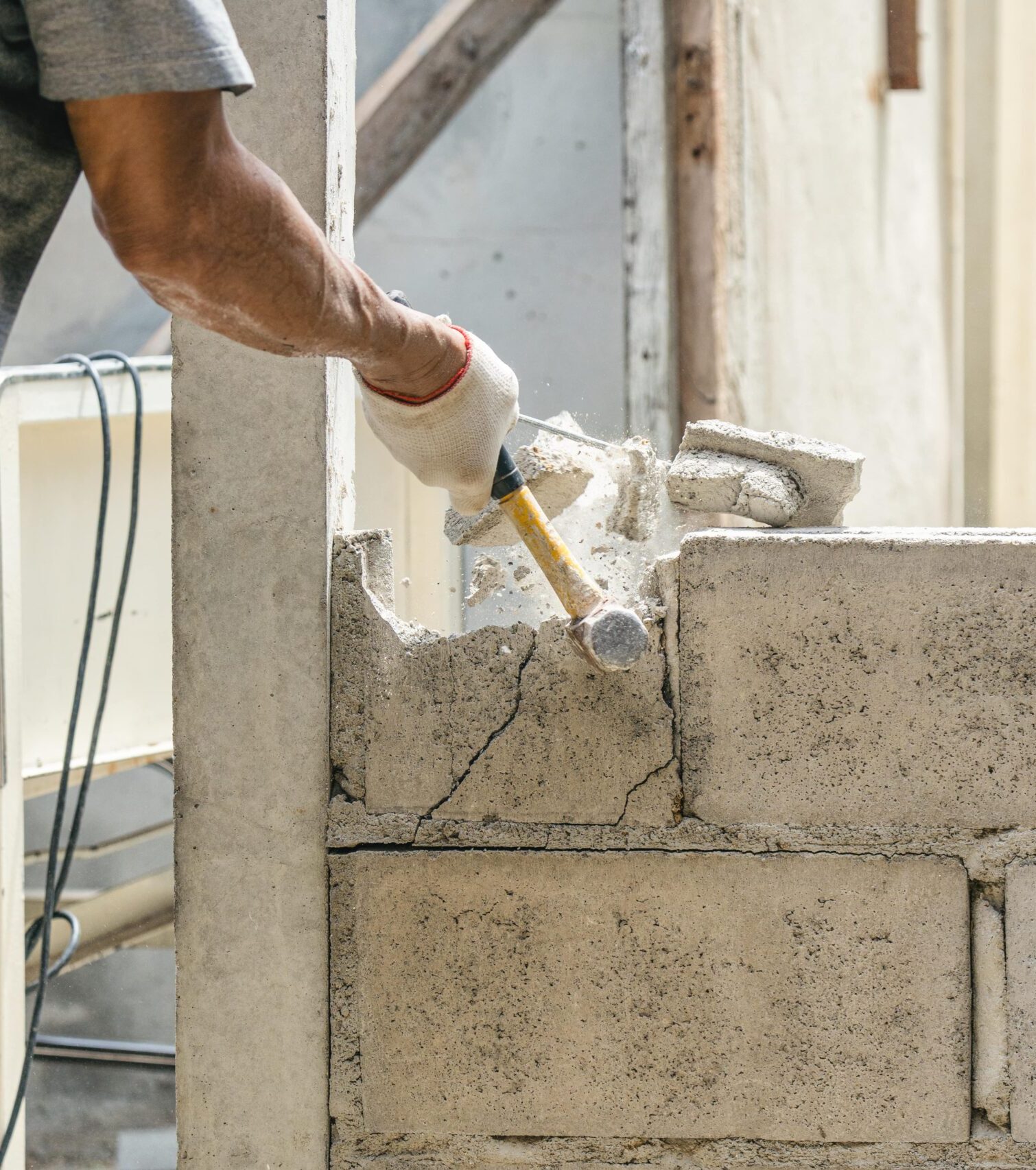 hand-worker-using-hammer-smashing-demolish-brick-wall-construction-site-min